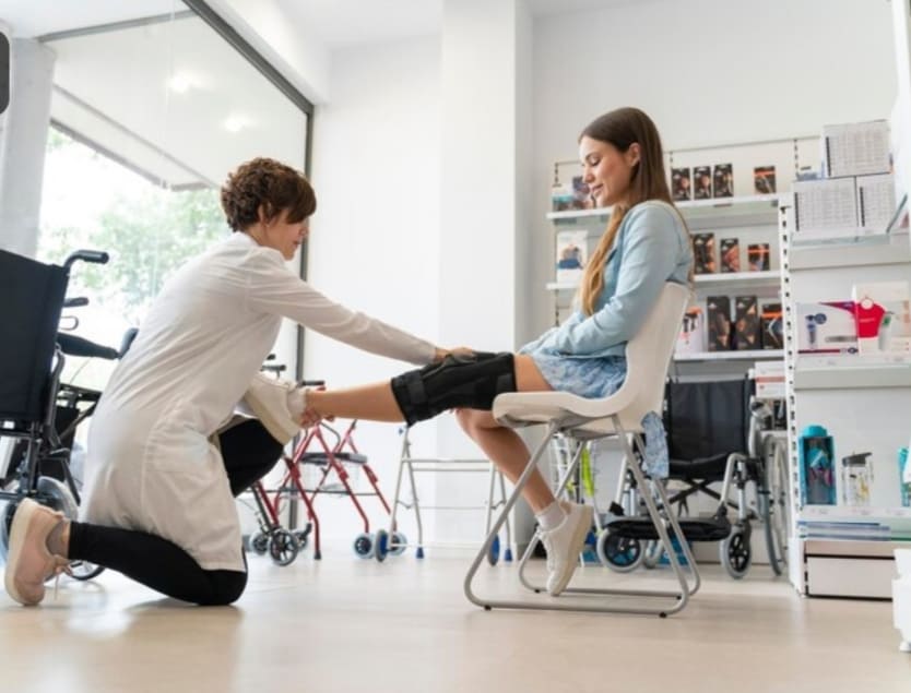 paciente sentada recibiendo evaluacion ortopedica de pierna en consulta con profesional de salud