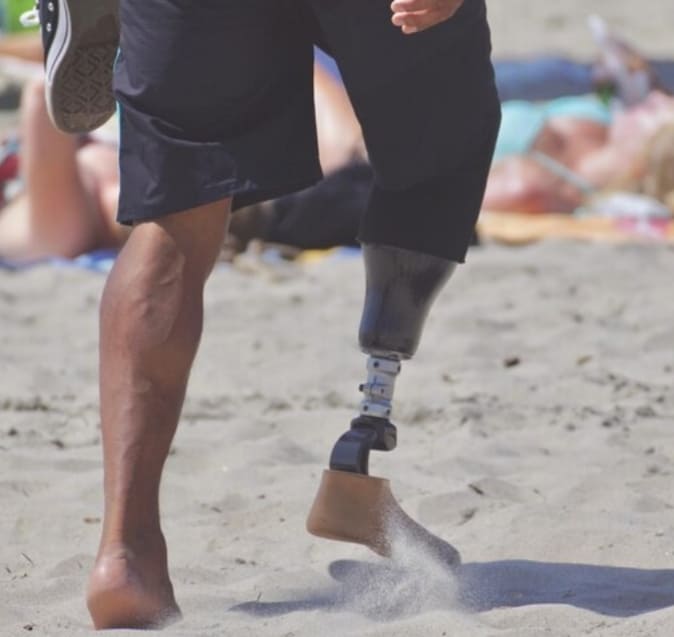 hombre corriendo en la playa con protesis de pierna arena y movimiento deportivo